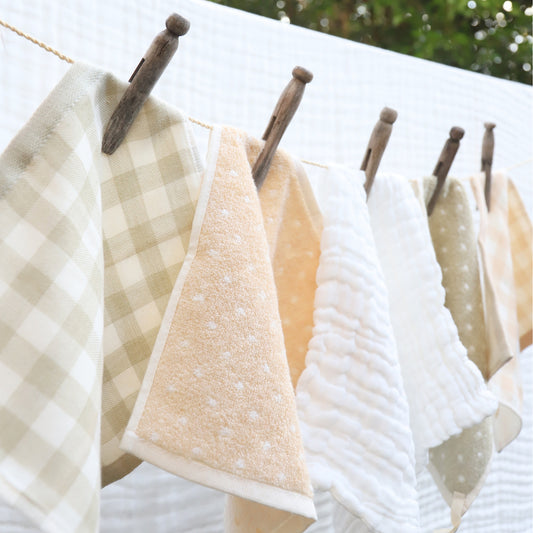 A set of organic cotton baby wipes hanging on a clothesline, displaying various natural colors and patterns.