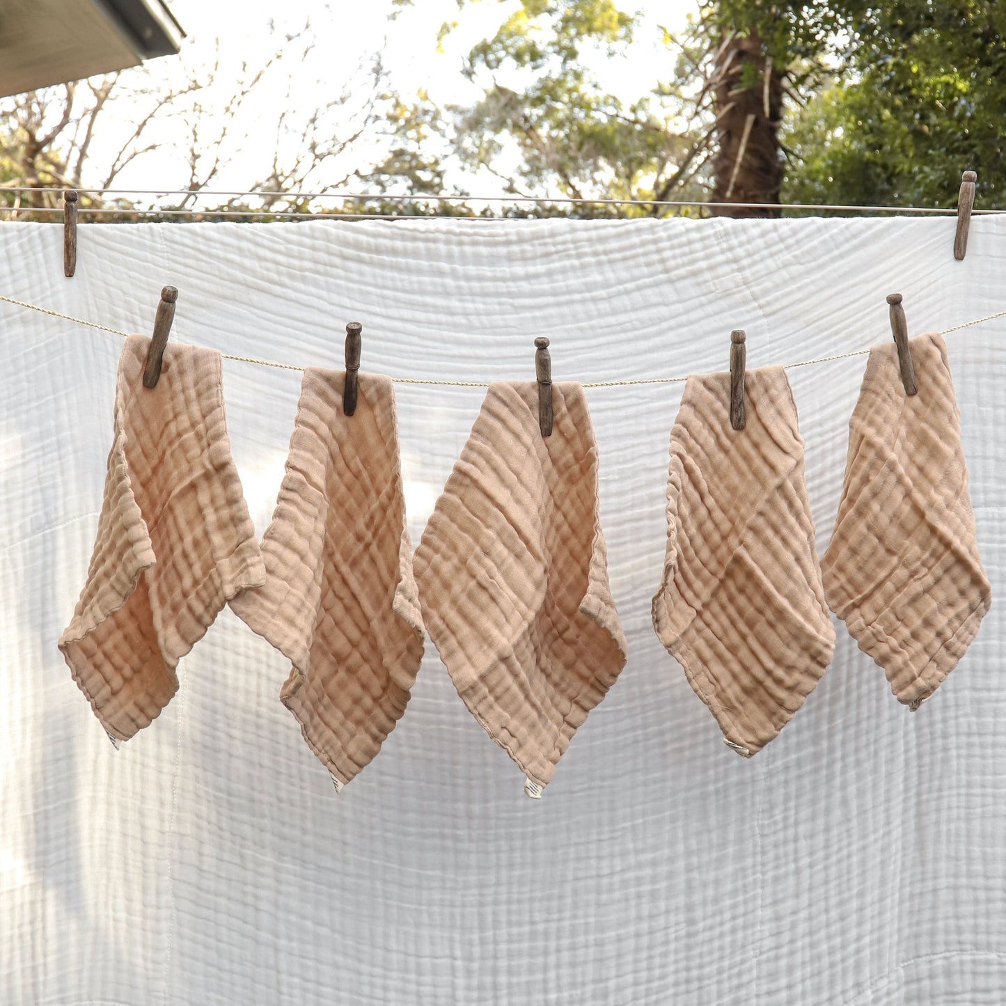 Woven plant fiber wipes hanging on a clothesline outdoors with trees in the background.