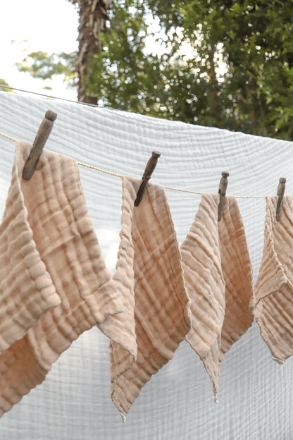 Textured fabric cloths hanging on a clothesline with trees in the background